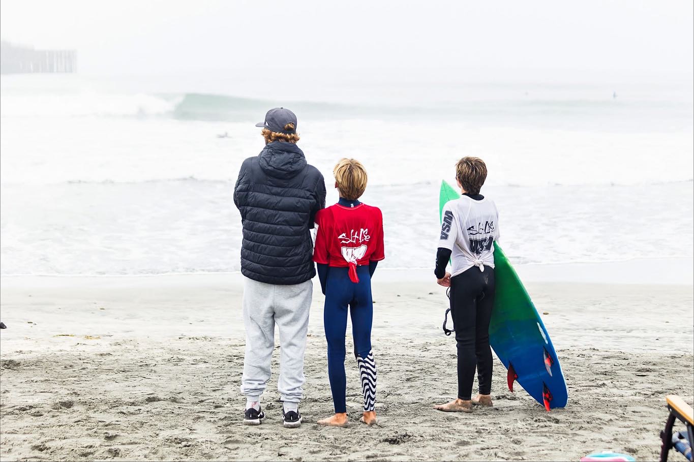 Coach watching the lineup with two young surfers