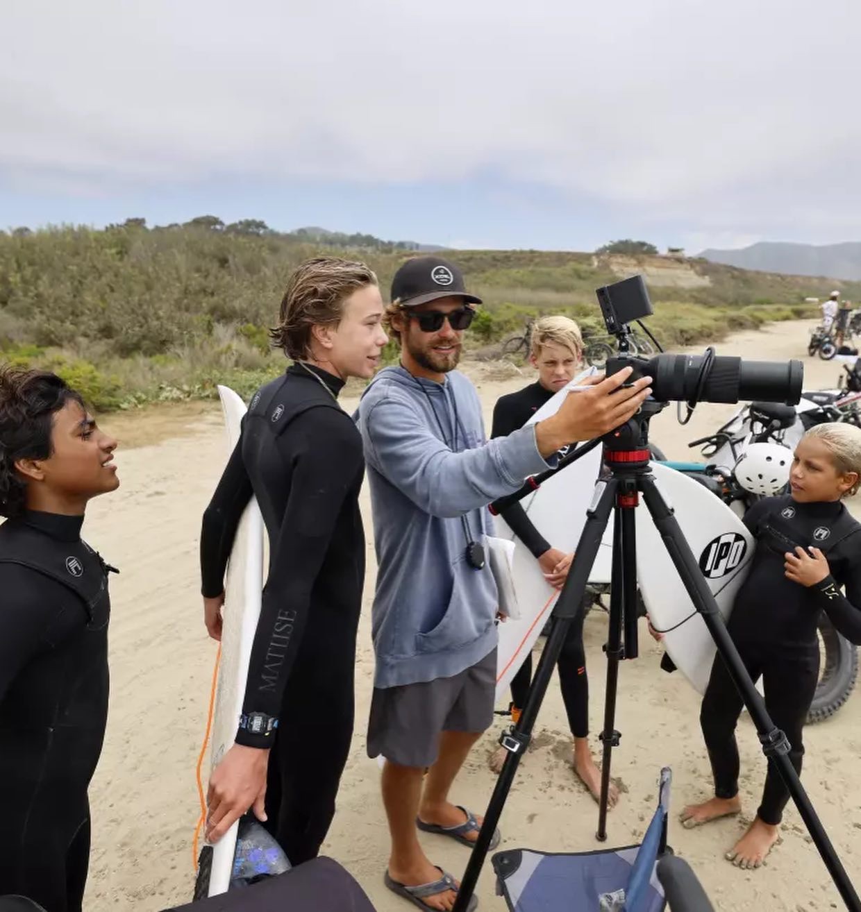 Lucas filming young surfers with a camera on a tripod