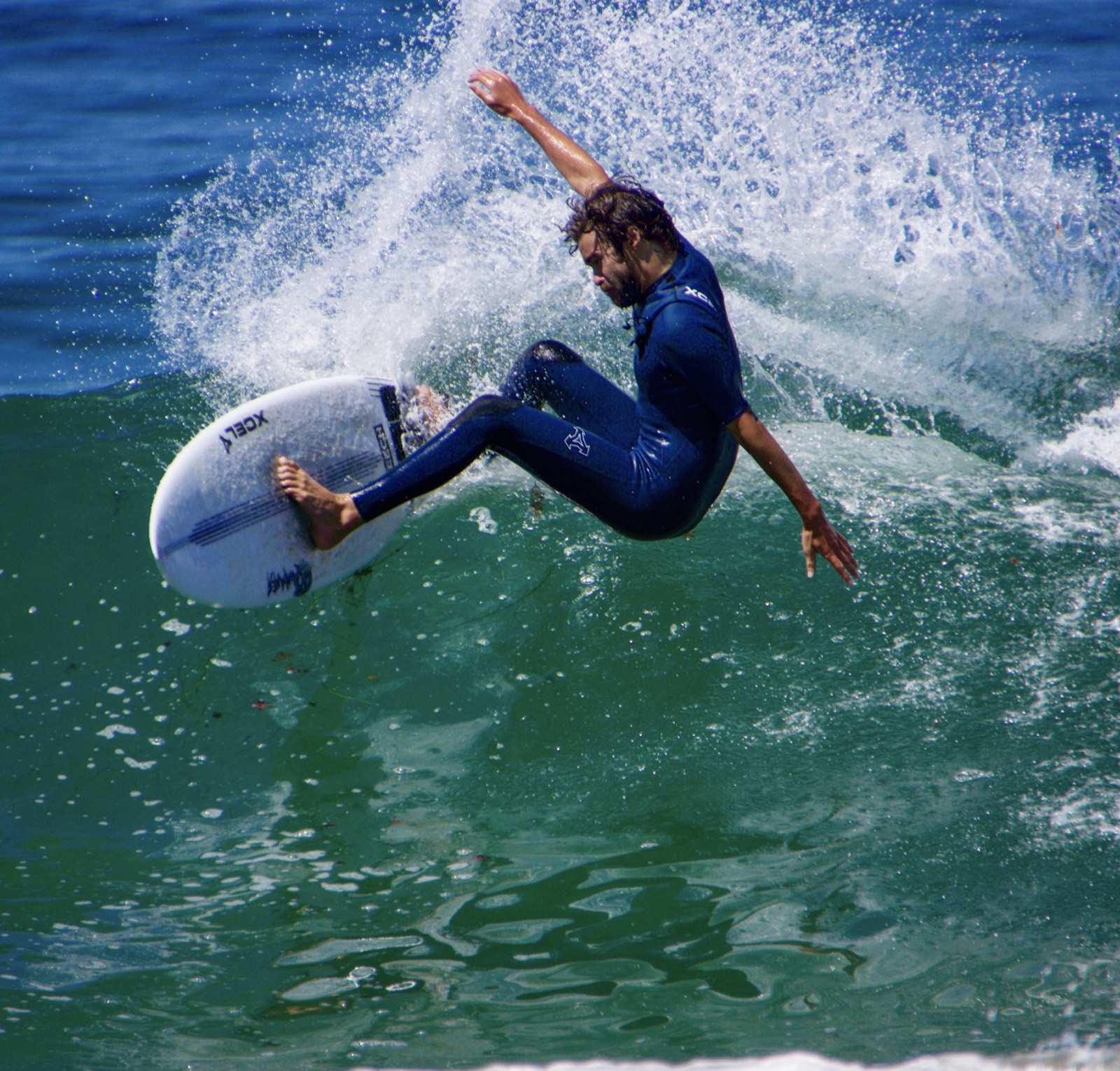 Lucas Taub hitting the lip in a blue wetsuit, throwing spray
