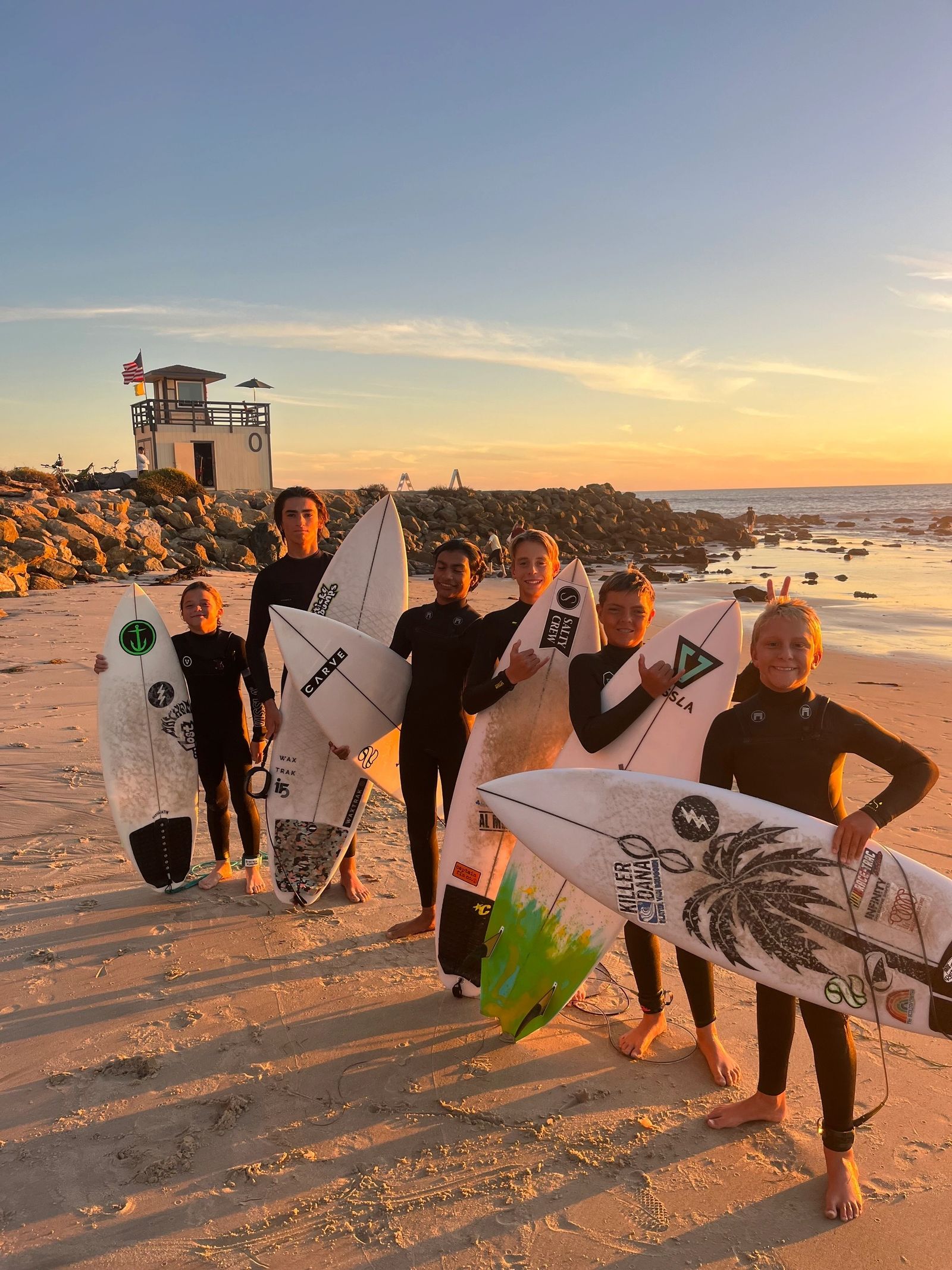 DP Surfcoach groms together on the beach at sunset with their boards